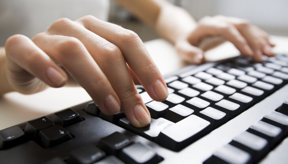 Close-up of female hands touching buttons of black computer keyboard