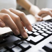 Close-up of female hands touching buttons of black computer keyboard