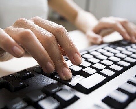 Close-up of female hands touching buttons of black computer keyboard